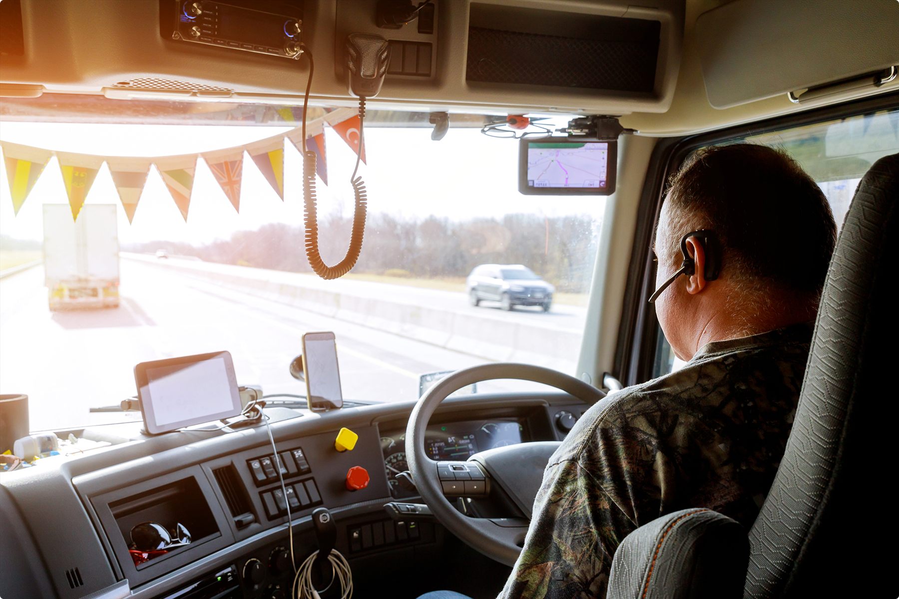 A truck driver looking out the side window at the highway while another vehicle passes.